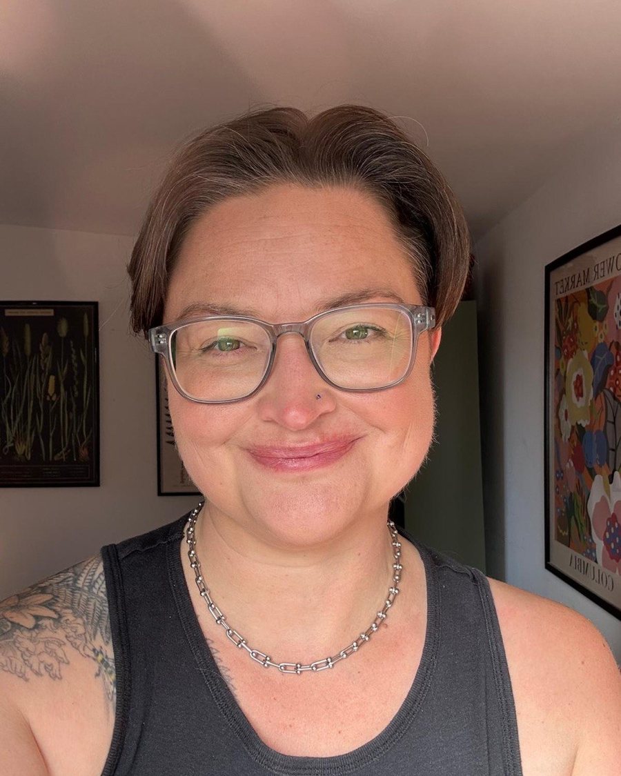 A close up of Delia smiling, wearing glasses, in her counselling room.